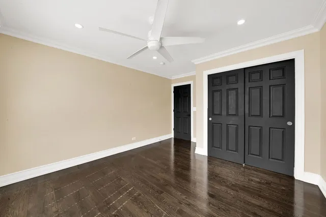 an empty room with wooden floor closet and windows