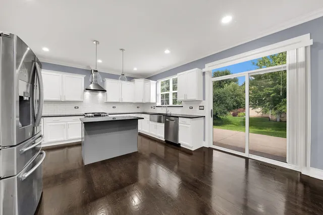 a large kitchen with kitchen island a large counter top space a sink stainless steel appliances and cabinets