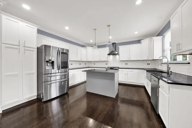 a kitchen with a refrigerator a sink and wooden floor