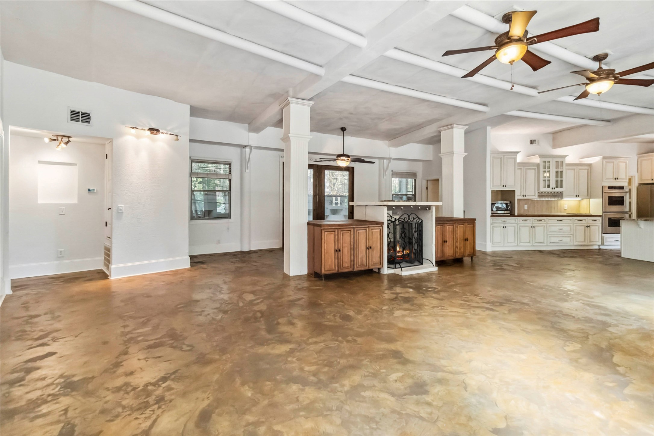 208 Old Potato Road Paige, TX 78659 - Photo 10 of 40 Living room, ceiling fan, concrete flooring, beamed ceiling, ornate columns, and a fireplace