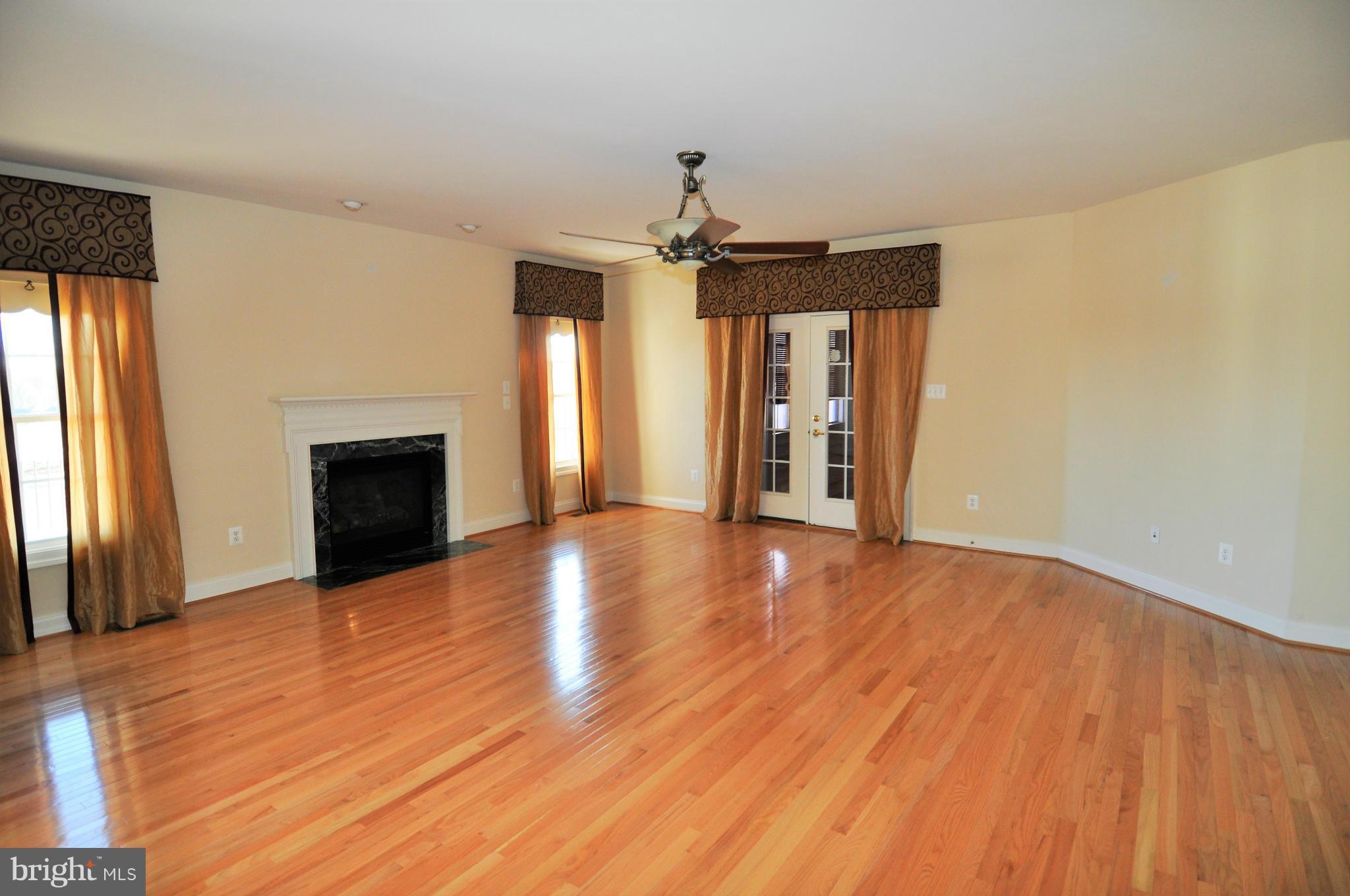 10827 Catron Road Perry Hall, MD 21128 - Photo 3 of 27 an empty room with wooden floor fireplace and windows