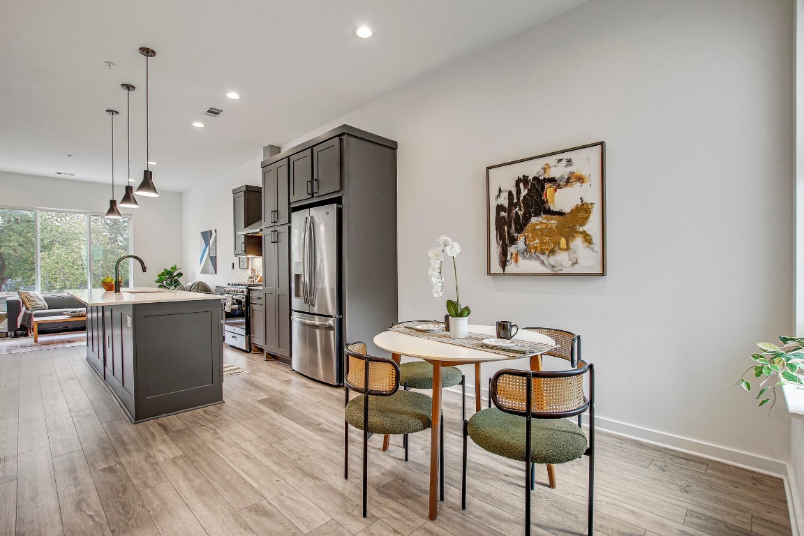 2804 South 1st Street, Unit 1108 Austin, TX 78704 - Photo 8 of 40 a kitchen with stainless steel appliances kitchen island granite countertop a refrigerator a stove a dining table and chairs with wooden floor