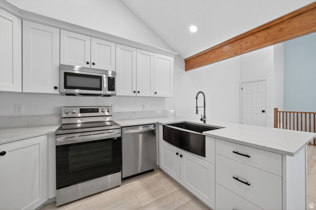 6969 South 855 East Midvale, UT 84047 - Photo 4 of 55 Modern kitchen featuring white cabinetry, stainless steel appliances, a black farmhouse sink, and light wood-finish flooring