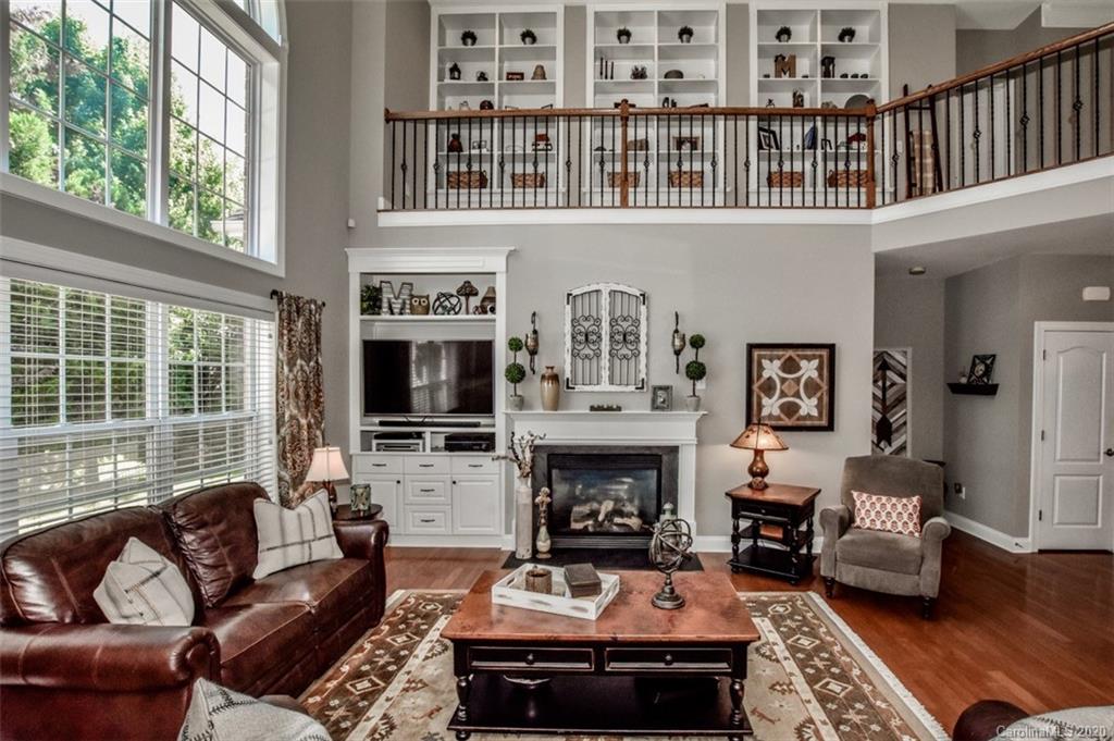 8723 Savannah Road Harrisburg, NC 28075 - Photo 11 of 44 a living room with furniture a fireplace and a floor to ceiling window