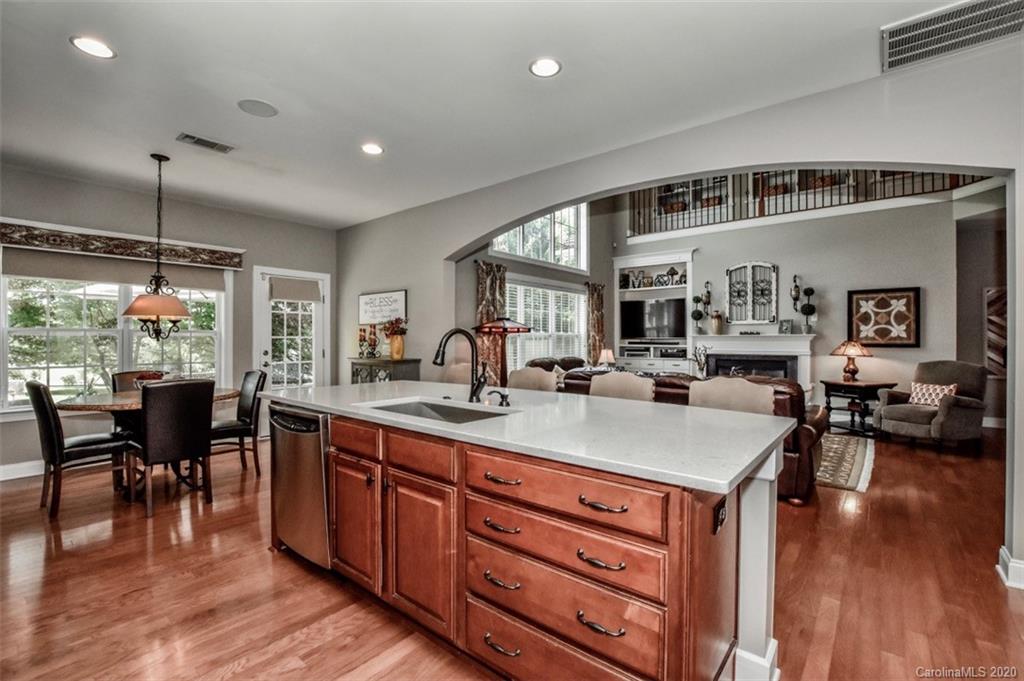 8723 Savannah Road Harrisburg, NC 28075 - Photo 13 of 44 a open kitchen with stainless steel appliances granite countertop a stove top oven a dining table and chairs with wooden floor