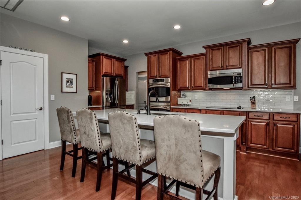 8723 Savannah Road Harrisburg, NC 28075 - Photo 14 of 44 a kitchen with stainless steel appliances granite countertop wooden floor cabinets dining table and chairs