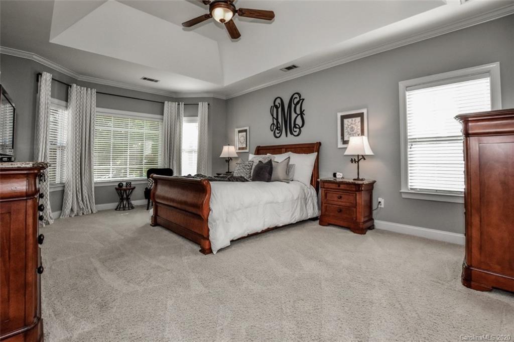 8723 Savannah Road Harrisburg, NC 28075 - Photo 18 of 44 a spacious bedroom with a bed a couch and a chandelier