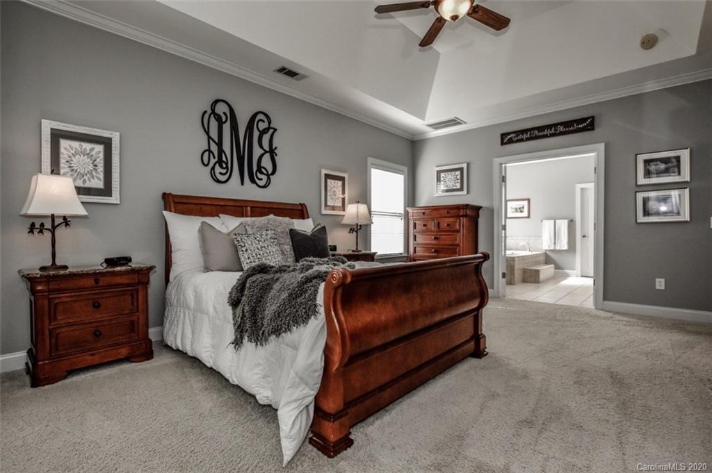 8723 Savannah Road Harrisburg, NC 28075 - Photo 20 of 44 a bedroom with a bed and a chandelier