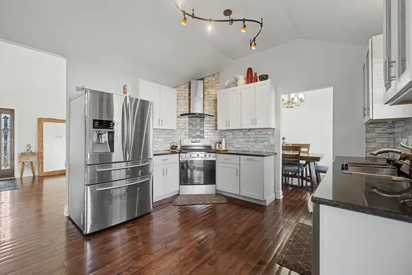 a kitchen with refrigerator a stove and wooden floor
