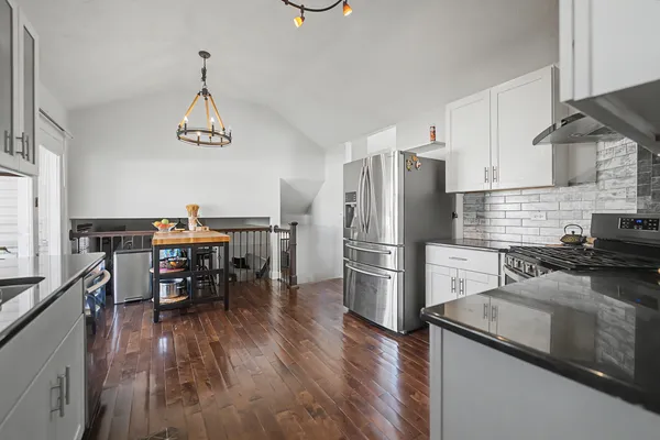 a kitchen with stainless steel appliances a dining table chairs stove and refrigerator