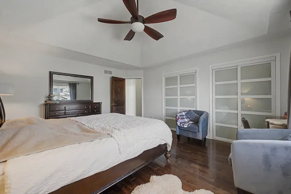 a bedroom with a bed and dresser with wooden floor