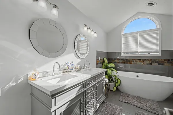a bathroom with a bathtub a double vanity sink and a mirror