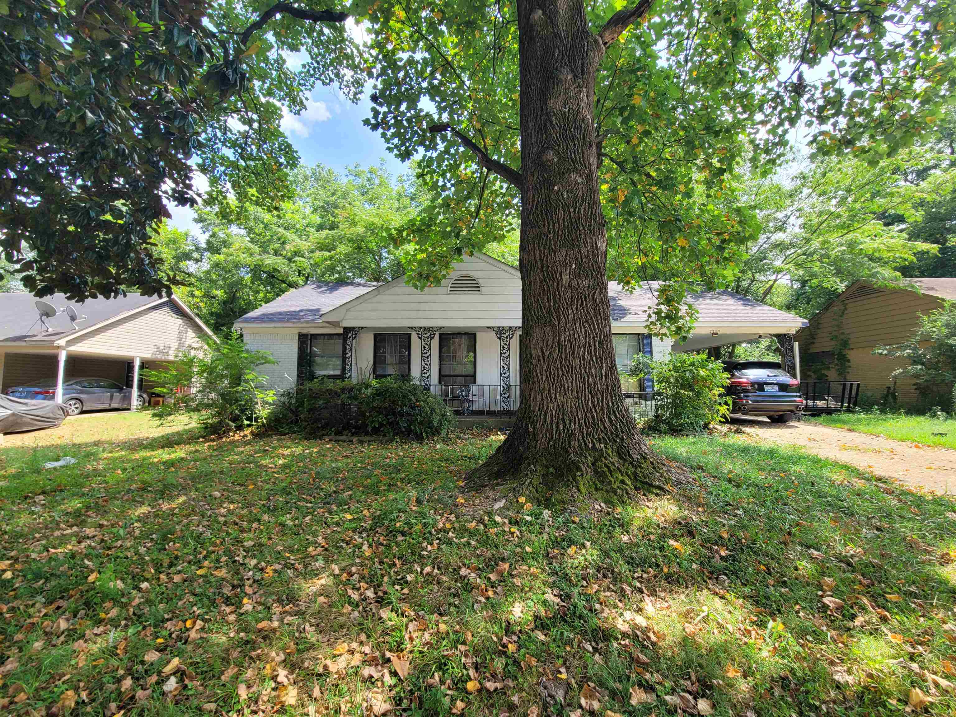 Bungalow-style home with a front yard, covered porch, driveway, and a carport