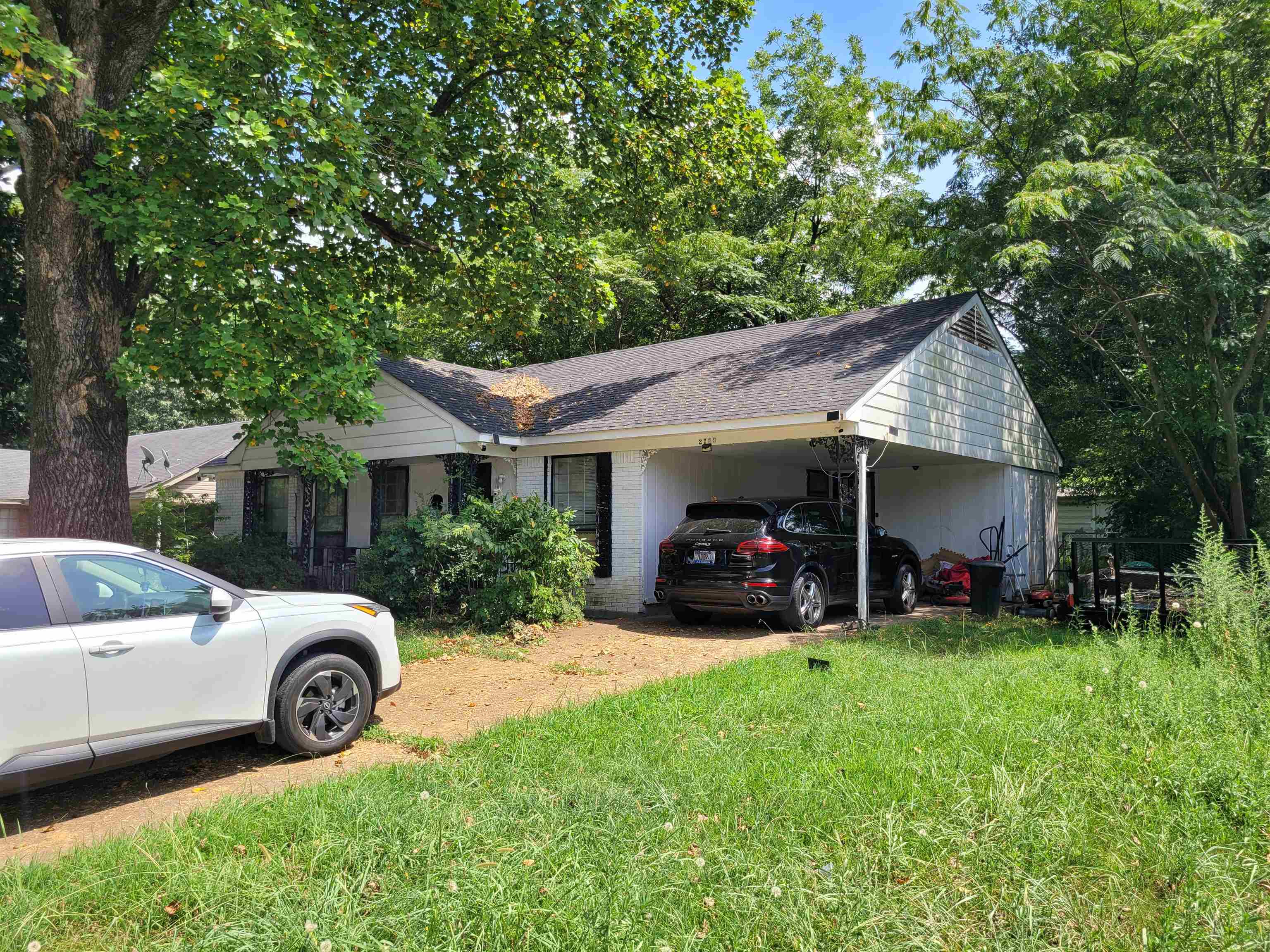 View of home's exterior with an attached carport, a shingled roof, a lawn, and brick siding