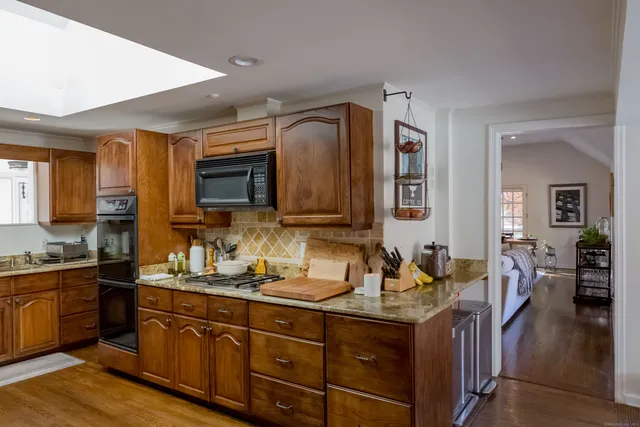 a kitchen with stainless steel appliances granite countertop a sink dishwasher stove and wooden cabinets
