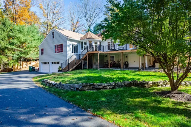 a view of a house with a yard deck and a large tree