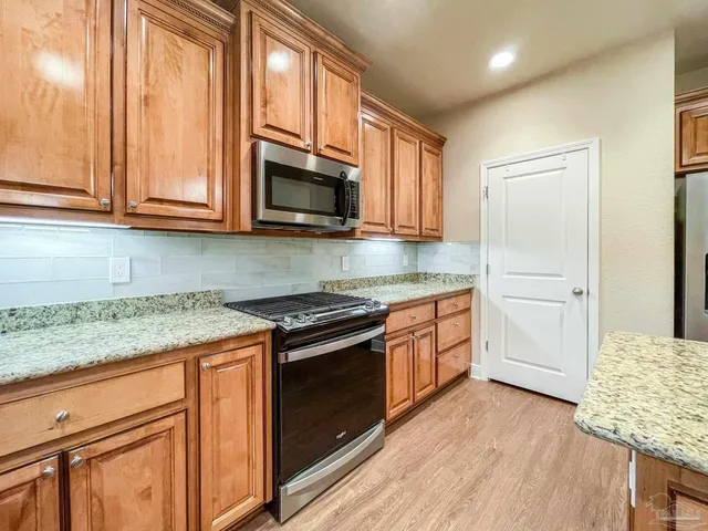a kitchen with stainless steel appliances granite countertop a stove a sink and a microwave