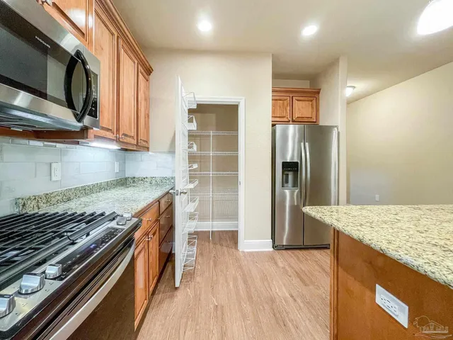 a kitchen with stainless steel appliances granite countertop a refrigerator and a stove top oven