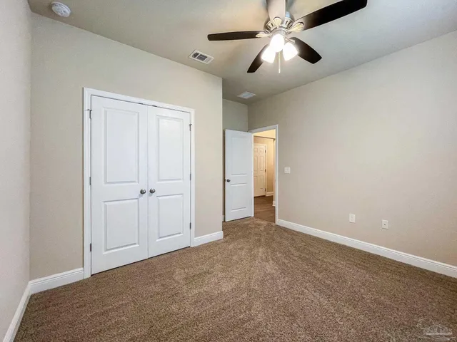 a view of an empty room and chandelier fan