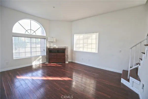 an empty room with wooden floor cabinet and windows