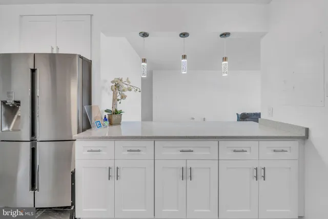 a kitchen with white cabinets and refrigerator