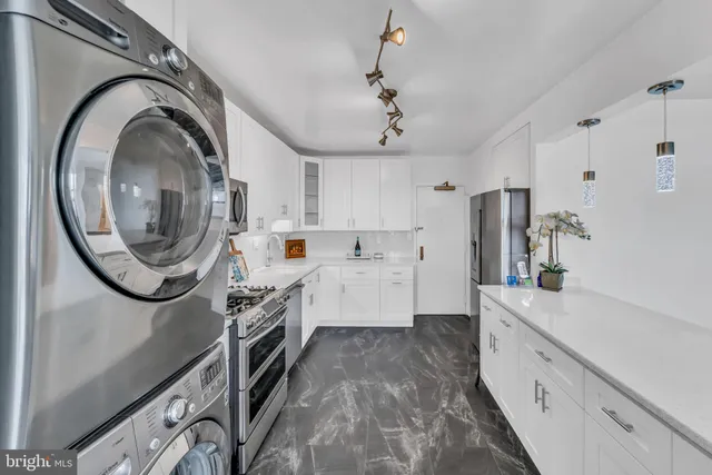 a large white kitchen with a sink a washer and dryer