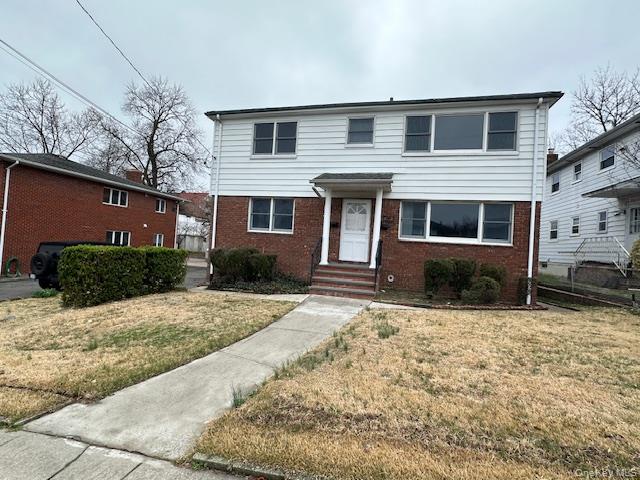 Traditional home with brick siding and a front lawn