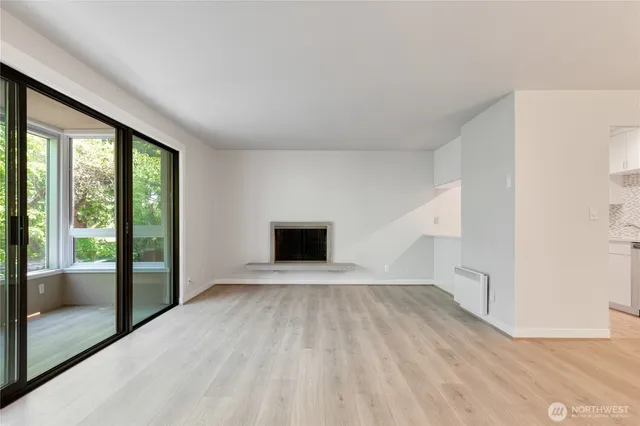 a view of an empty room with a window and wooden floor