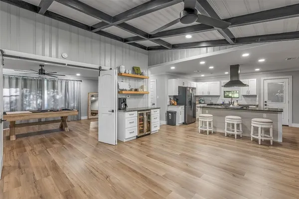 a kitchen with stainless steel appliances kitchen island granite countertop a refrigerator a oven a stove and white cabinets with wooden floor