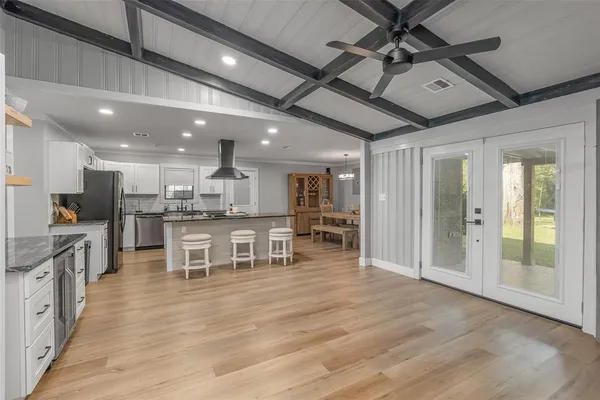 a view of a kitchen with kitchen island stainless steel appliances wooden floor dining table and chairs