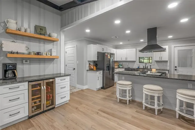 a kitchen with stainless steel appliances kitchen island granite countertop a table chairs stove and cabinets