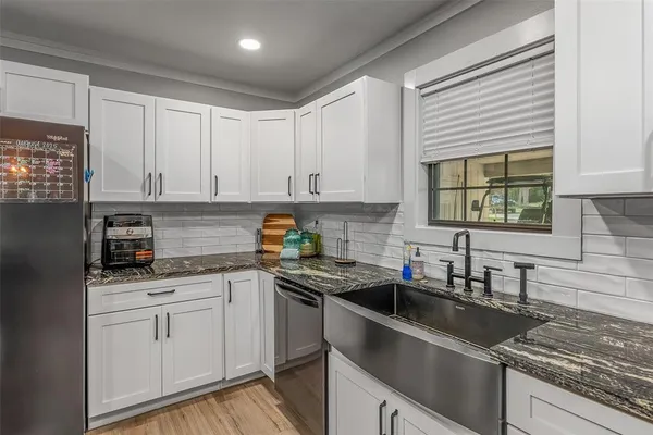 a kitchen with granite countertop stainless steel appliances a stove refrigerator and cabinets
