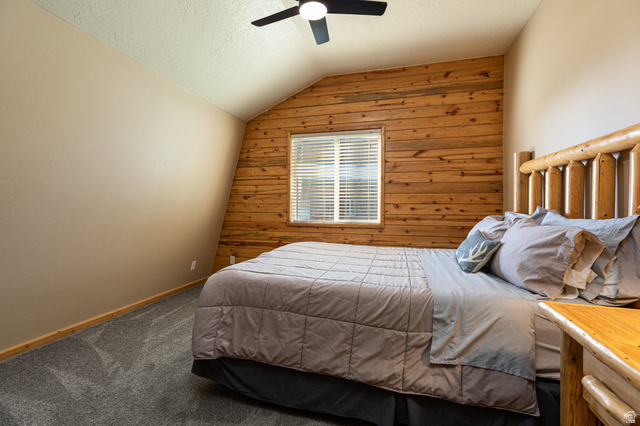 1505 West Elk Ridge Drive Alton, UT 84710 - Photo 22 of 53 Bedroom with wood walls, lofted ceiling, a textured ceiling, carpet floors, and a ceiling fan
