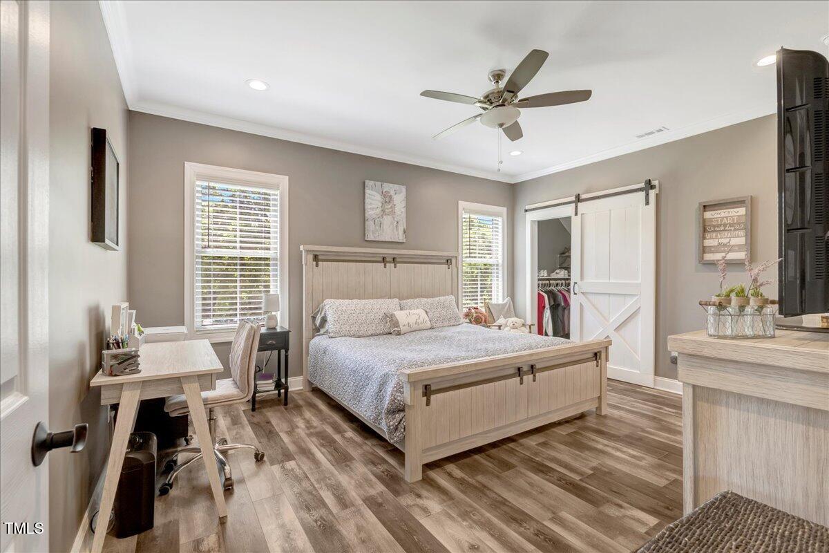 2258 Sanders Road Stem, NC 27581 - Photo 13 of 42 a bedroom with a large bed and a chandelier