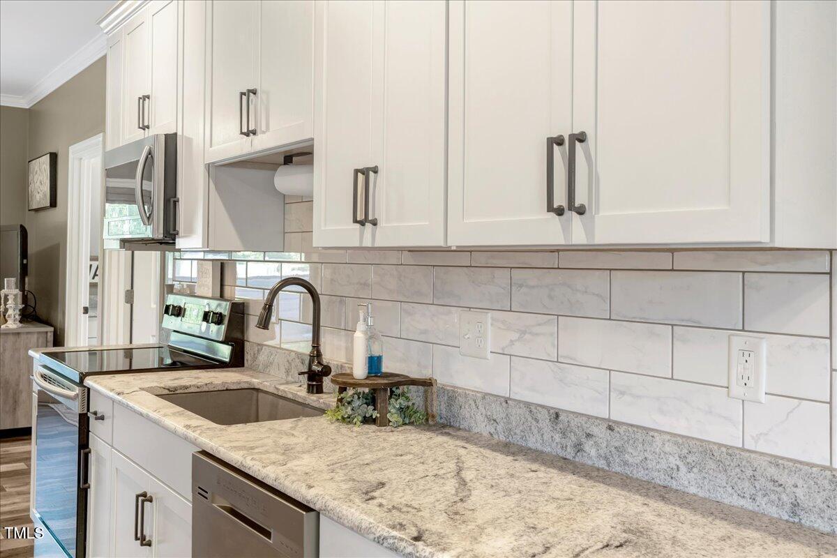 2258 Sanders Road Stem, NC 27581 - Photo 9 of 42 a kitchen with granite countertop a sink and a stove