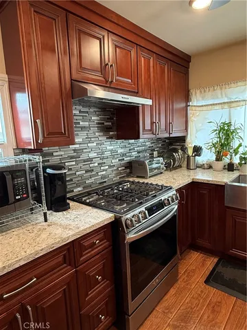 a kitchen with stainless steel appliances granite countertop a stove a sink and a microwave