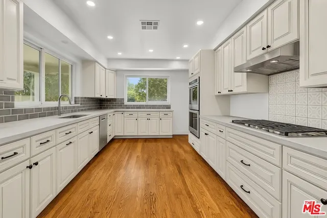 a large kitchen with cabinets wooden floor and stainless steel appliances