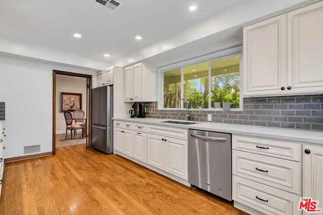 a kitchen with granite countertop a sink stainless steel appliances and cabinets