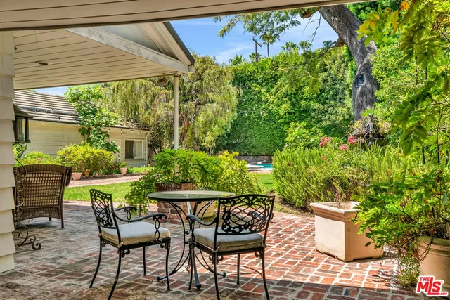 a patio with table and chairs and potted plants