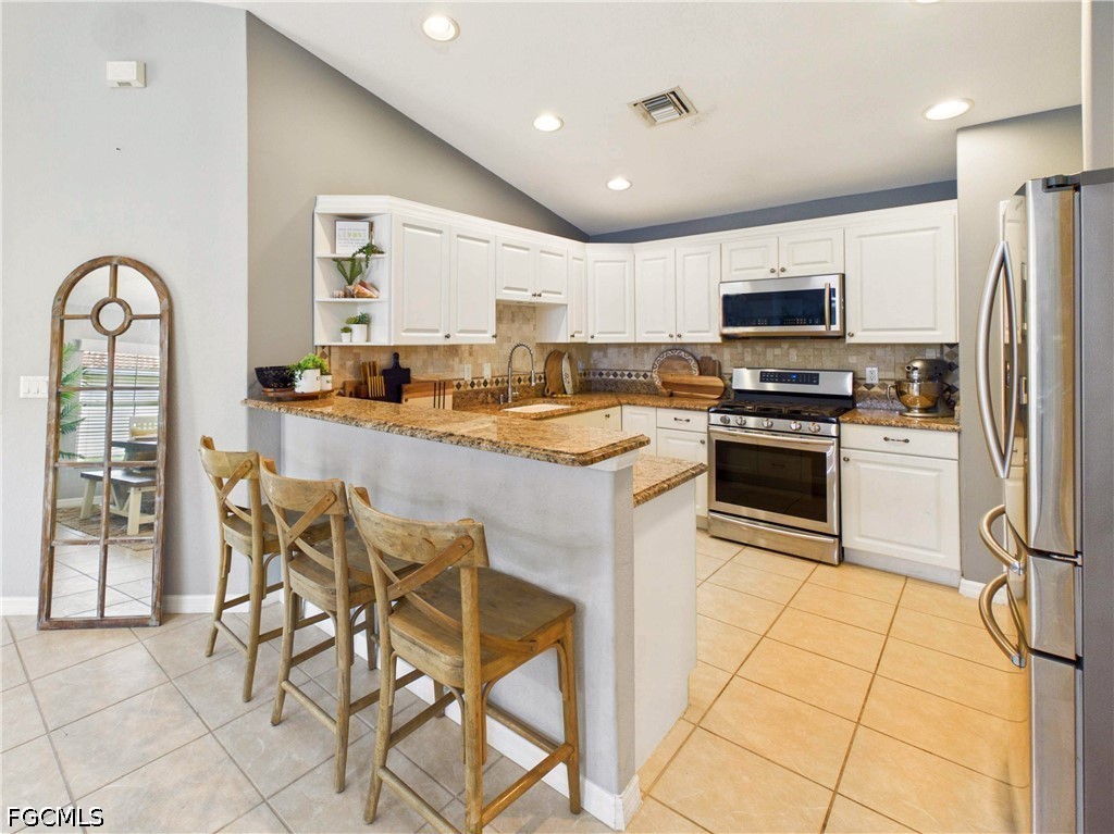 19694 Villa Rosa Loop Estero, FL 33967 - Photo 12 of 28 a kitchen with stainless steel appliances granite countertop a stove a sink a microwave and a refrigerator
