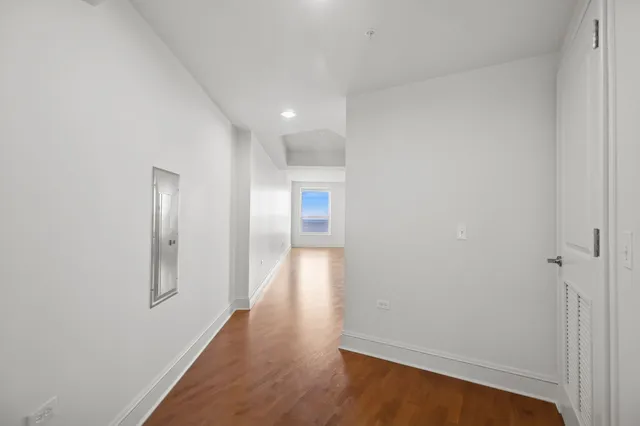 a view of an empty room with wooden floor and cabinets