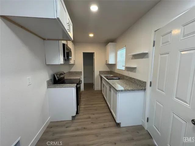 a kitchen with granite countertop a sink stove and refrigerator