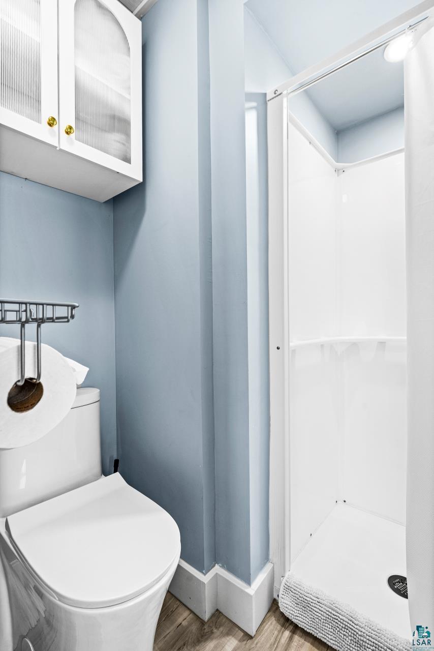 3645 Haines Road Hermantown, MN 55811 - Photo 23 of 35 Full bathroom featuring a white toilet, enclosed shower stall, and light blue wall finish