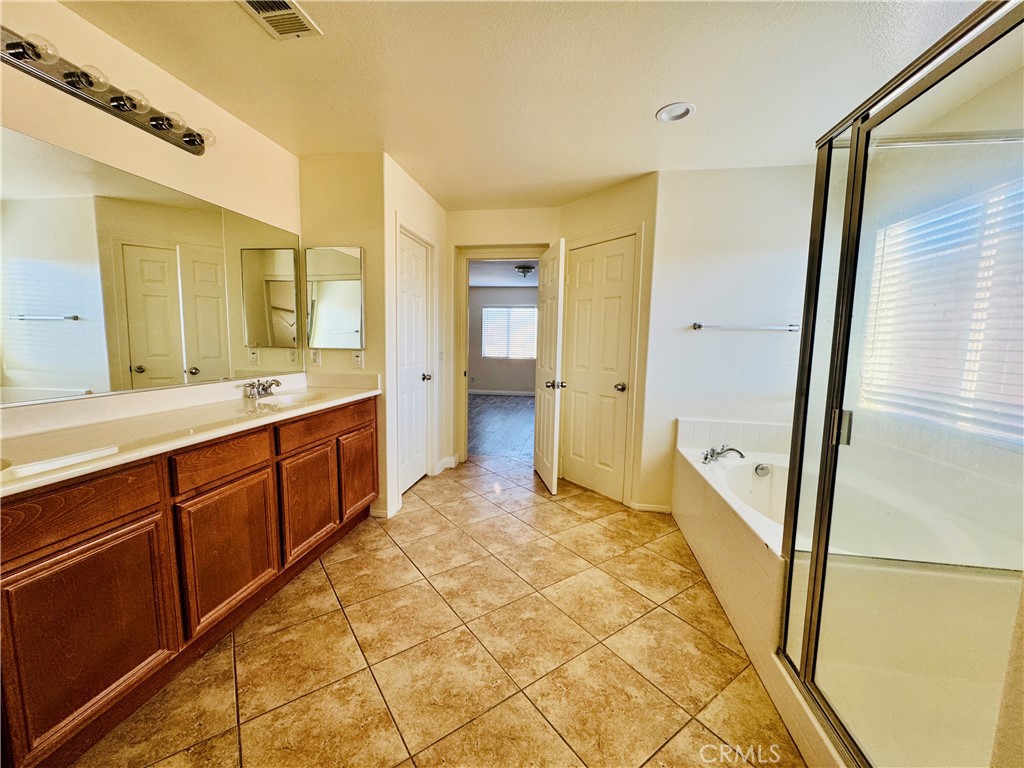 9329 Sable Ridge Avenue Hesperia, CA 92345 - Photo 26 of 31 a spacious bathroom with a double vanity sink a mirror and a shower