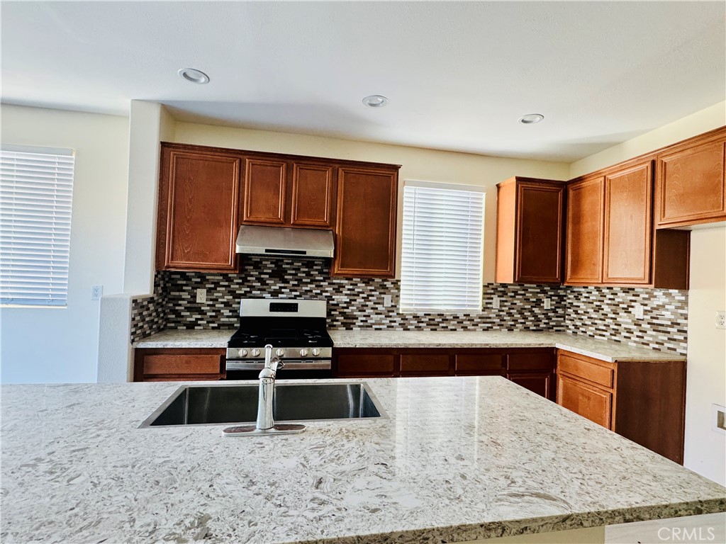 9329 Sable Ridge Avenue Hesperia, CA 92345 - Photo 6 of 31 a kitchen with stainless steel appliances kitchen island granite countertop a stove and a sink