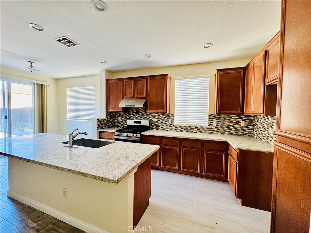 9329 Sable Ridge Avenue Hesperia, CA 92345 - Photo 7 of 31 a kitchen with stainless steel appliances granite countertop a sink stove and refrigerator