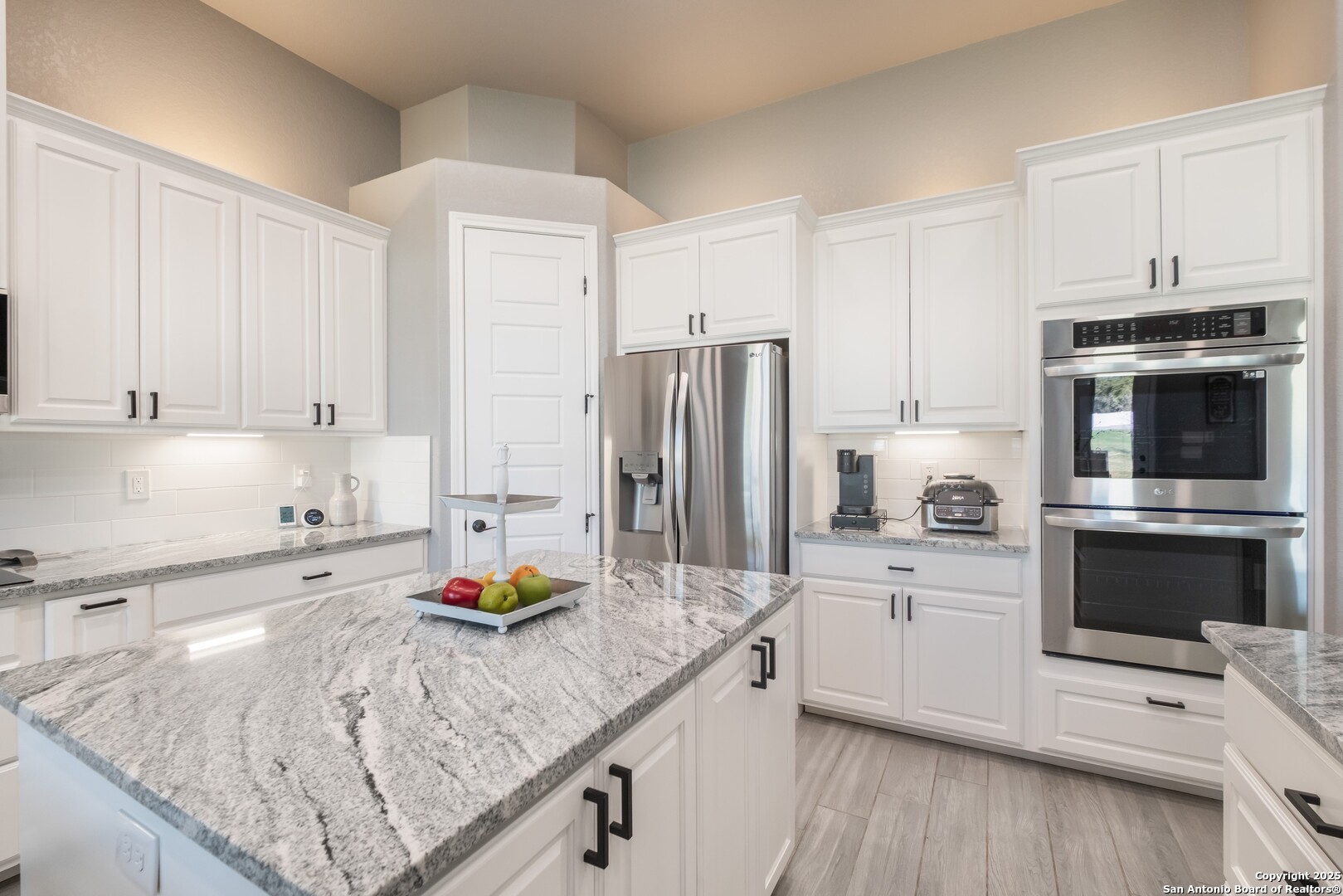 108 Timber Heights La Vernia, TX 78121 - Photo 15 of 42 a kitchen with stainless steel appliances granite countertop a refrigerator a stove and white cabinets with wooden floor