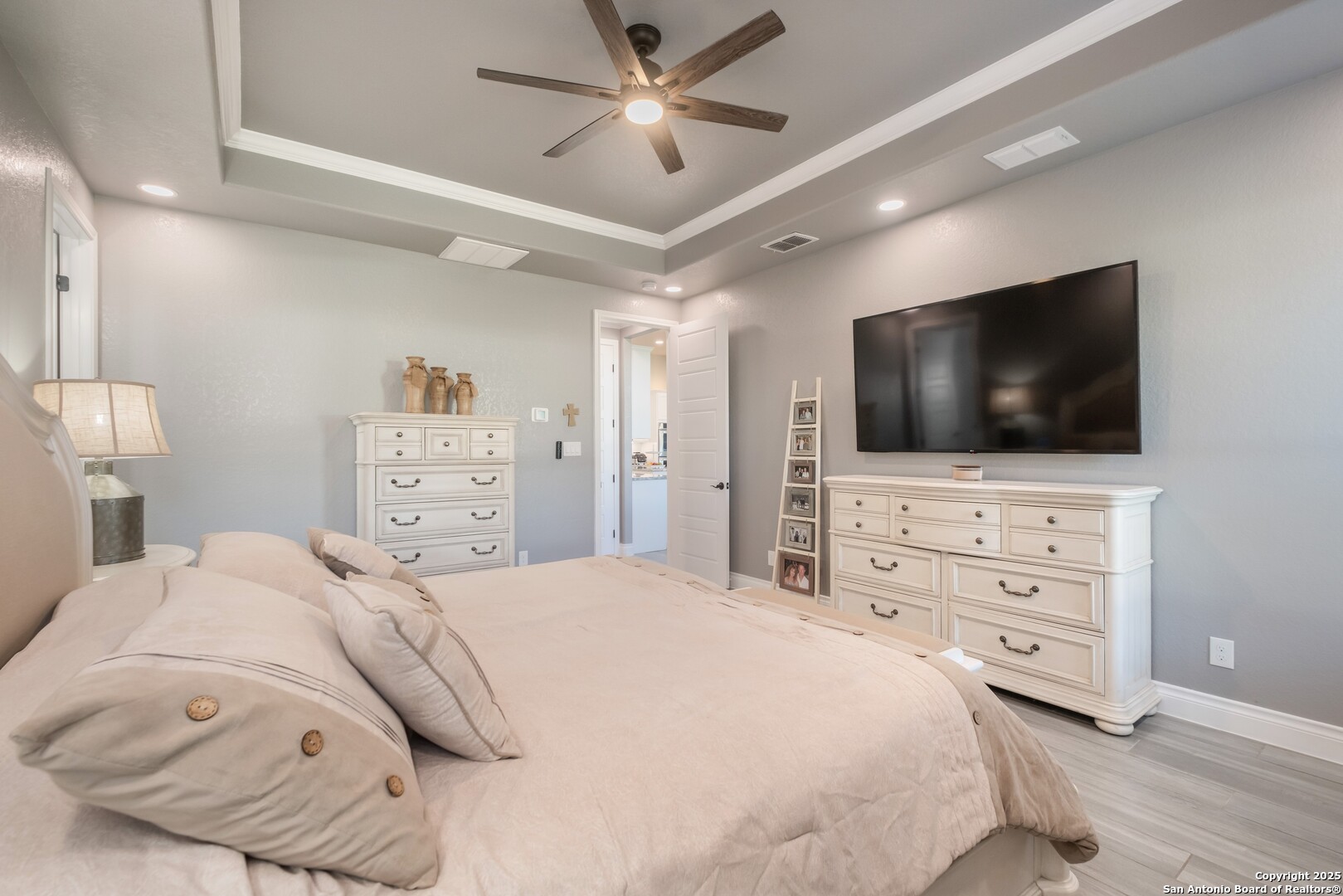 108 Timber Heights La Vernia, TX 78121 - Photo 19 of 42 a bedroom with a bed a flat screen tv and a chandelier