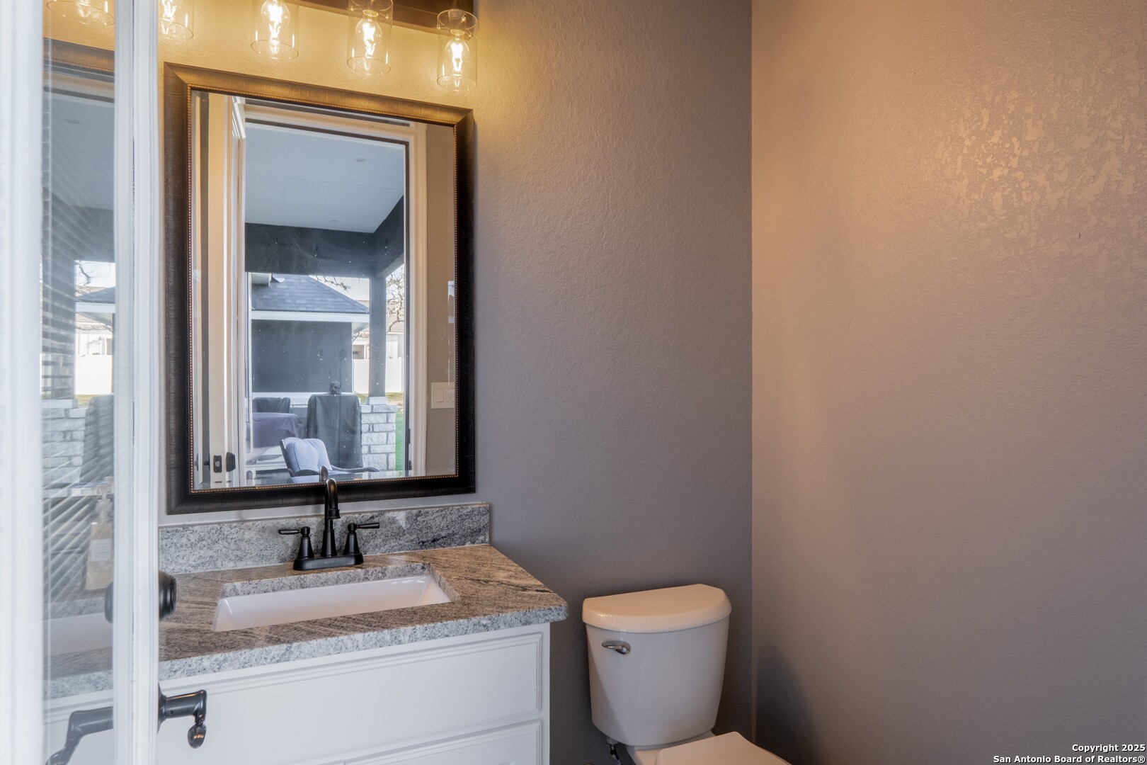 108 Timber Heights La Vernia, TX 78121 - Photo 35 of 42 a bathroom with a granite countertop toilet a sink and mirror