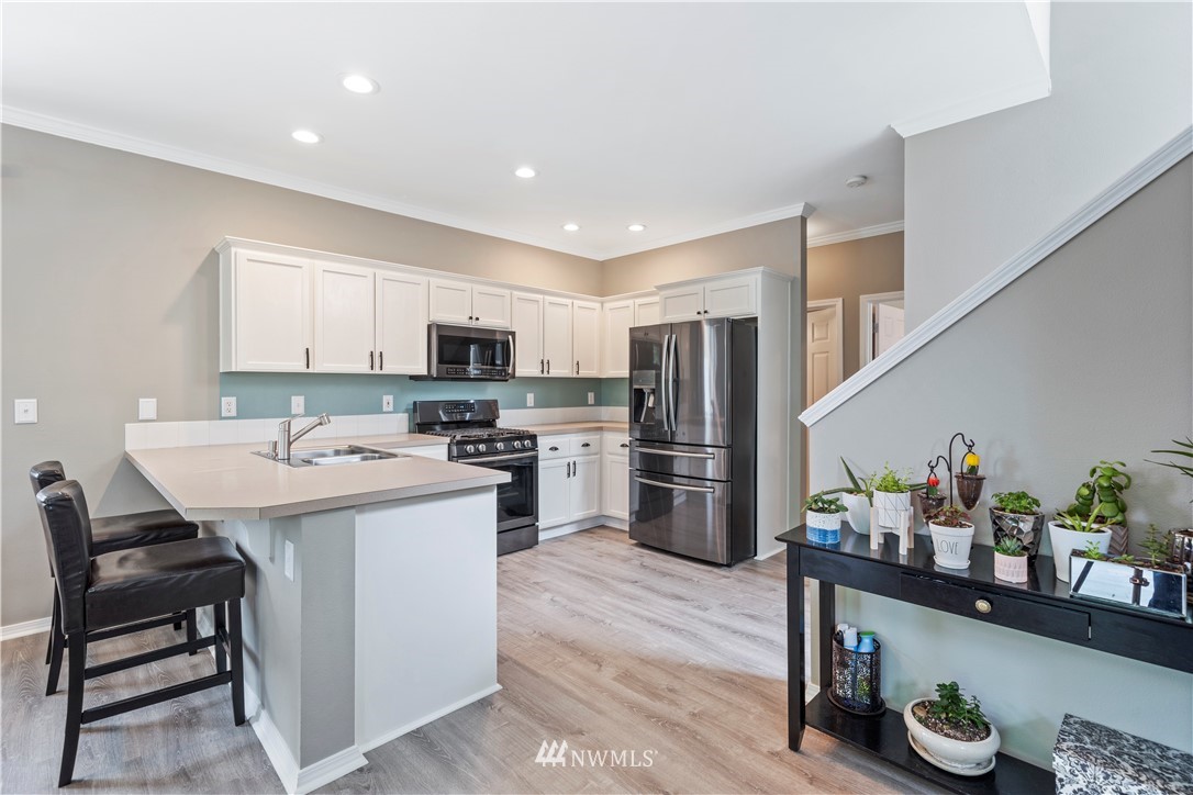 1162 Edmonds Place Northeast Renton, WA 98056 - Photo 12 of 25 a kitchen with stainless steel appliances a sink a stove a refrigerator cabinets and wooden floor